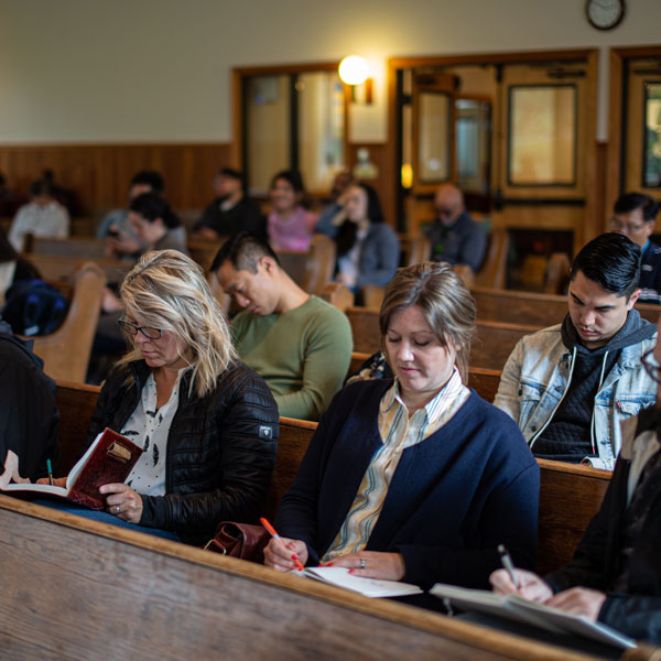 Seminary students sit in pews writing notes