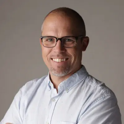 Portrait of Ben Sand in a grey shirt and glasses