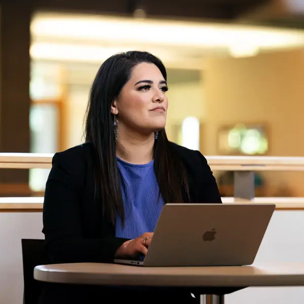 Student looks off to the side contemplatively while workin on her computer