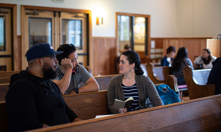 3 people sit in pews in a church