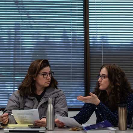 2 students sit in class with discussing classwork