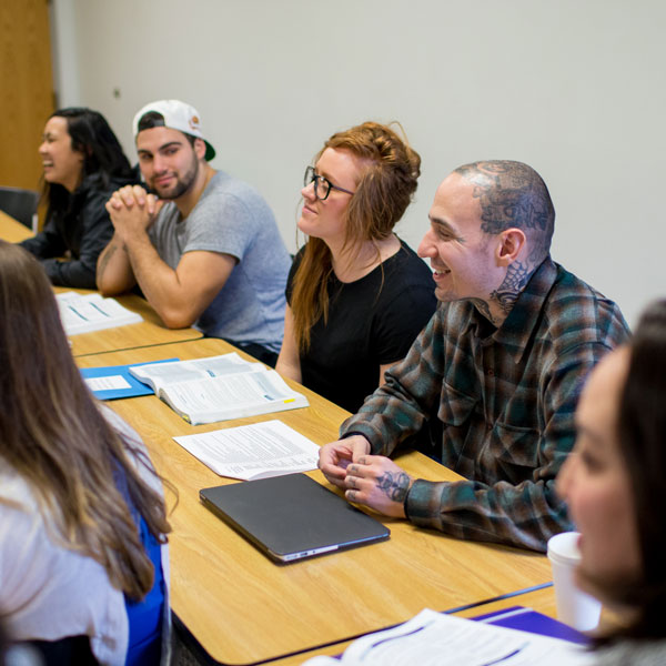 4 students sit in the back row of of a classroom