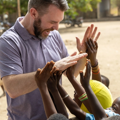 Trevor Owen giving high-fives to a group of children