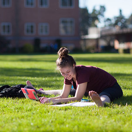 A student working on her laptop outside.