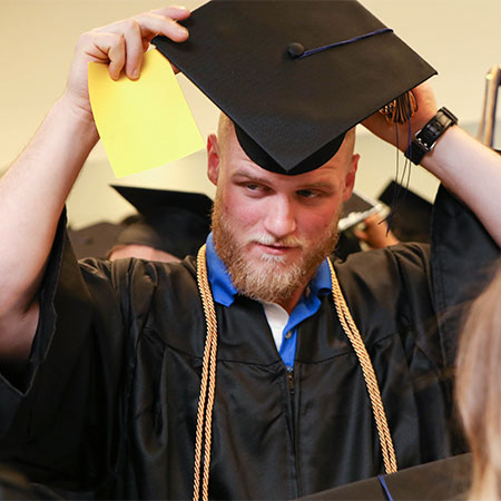 A graduate putting his cap on